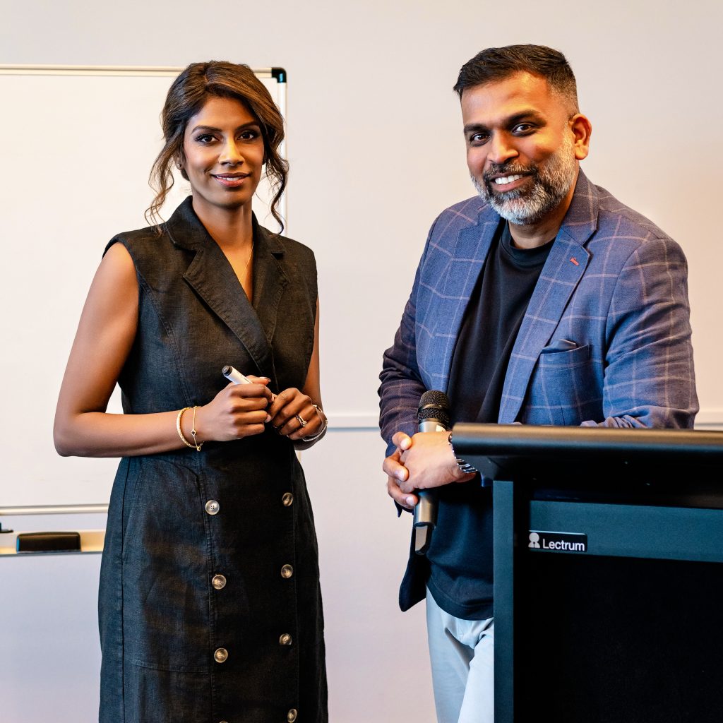 Two professionals standing at a podium and whiteboard in a conference room, prepared to speak at a seminar or business presentation