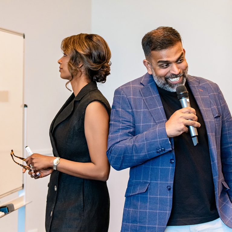 Light & Glo co-founders delivering a joint workshop or keynote presentation, engaging a live audience with humour and insight in a corporate event setting.